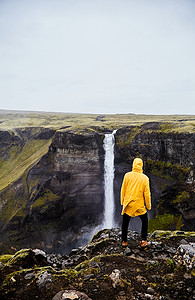 冰岛瀑布 Haifoss。一个年轻的家伙站在悬崖上, 看着瀑布. 