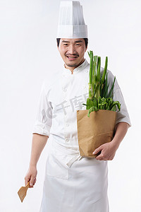 抱着蔬菜摄影照片_穿着厨师服的中年男人抱着蔬菜