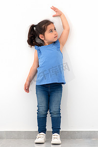 小女孩在白墙附近测量身高.