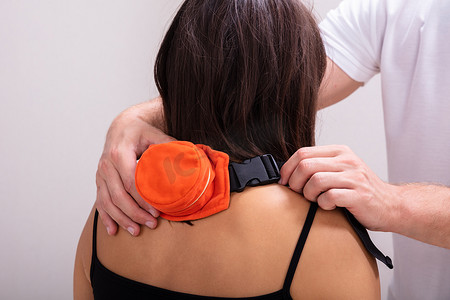 一位男性治疗师在女性患者背上系着莫沙腰带的特写