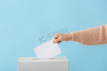 肤色背景的投票箱附近的投票妇女