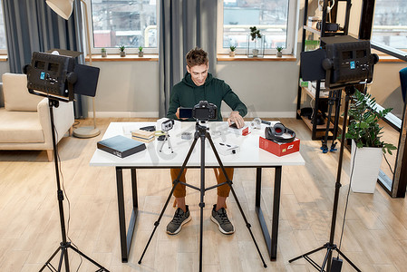 work摄影照片_年轻男性科技博主在家庭工作室录制有关新智能手机的视频博客或博客的全长照片。Blog, Work from Home concept