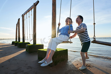 海边秋千摄影照片_快乐的老年夫妇在海边荡秋千