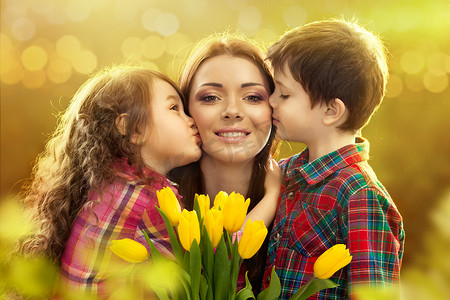 国际亲吻日摄影照片_快乐妈妈吻了她的女儿和儿子