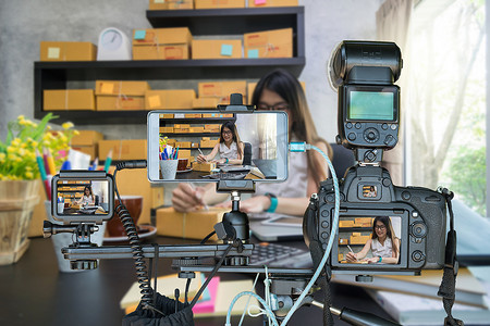 专业的相机与智能手机和动作摄像头在三脚架上的年轻企业妇女在家中进行网上购物, 为企业家概念直播流