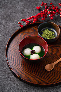 Close up of matcha big tangyuan (tang yuan) with sweet matcha soup in a bowl on wooden table background for festival food.