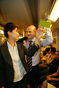 人群交谈摄影照片_上海地铁车厢内两位中外商务人士交谈
