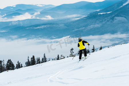 钢盔摄影照片_钢盔滑雪者在高山附近的斜坡上 