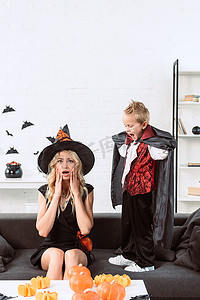 小男孩在吸血鬼服装在母亲尖叫在女巫万圣节服装在家里