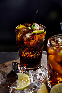 带吸管、冰块和韧带的玻璃杯中鸡尾酒方块的选择焦点，黑色背景 
