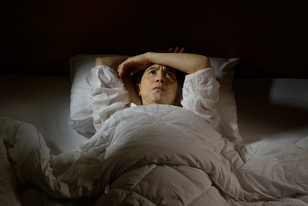 躺在床上摄影照片_失眠的妇女睁着眼躺在床上