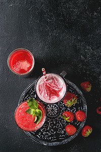 三种不同的红色水果浆果西瓜, 草莓, 覆盆子, 石榴鸡尾酒或冰沙, 在玻璃与粉碎冰, 新鲜薄荷, 成分以上黑色背景。平躺, 空间