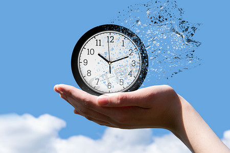 时间的终结或时间的飞行概念。一个女人的手拿着一个圆形的钟，箭头表示时间是十点十分，钟在蓝天的映衬下分成小碎片，可以看到前方的景象