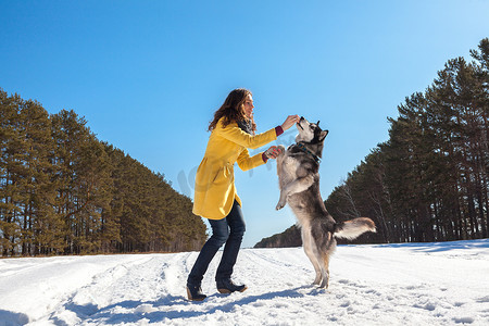 woman plays with dog in the winter forest
