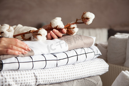 整整齐齐摄影照片_整整齐齐的女人手牵着棉枝，一堆堆叠得整整齐齐的床单、毛毯和毛巾。生产天然纤维.制造。有机产品.