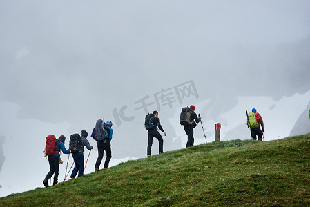 一群背着背包爬山的男性游客.勇敢无畏的高山主义者在多雾的悬崖峭壁上爬山.远足、旅行、登山和背包旅行的概念.
