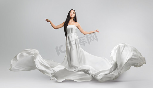 白布摄影照片_美丽的年轻女孩在飞行白色连衣裙。流动的织物。光白布飞在风中