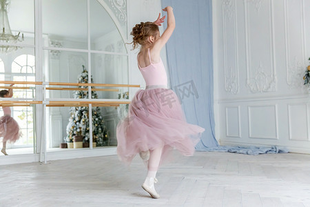 舞蹈课上年轻的古典芭蕾舞女.美丽优雅的芭蕾舞演员在白色灯堂的大镜子前练习穿着粉色短裙的芭蕾舞姿势