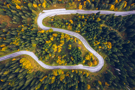 福摄影照片_弯弯曲曲的道路在森林里. 公路的空中图像。 福雷斯图样。 秋天从无人驾驶飞机上看到的弯曲的风景大道。 Zg zag绕行山路空中俯瞰，无人驾驶飞机发射.