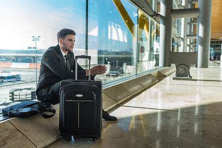 年轻的商人在机场焦急地等待着他的行李延误的飞行。