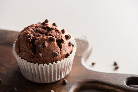 close摄影照片_close up view of fresh chocolate muffin on wooden cutting board