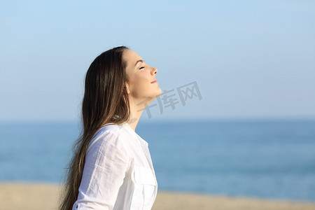 呼吸空气摄影照片_海滩上呼吸新鲜空气的妇女