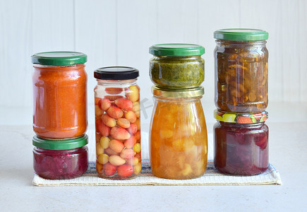 在玻璃瓶中保存的各种食品-泡菜, 果酱, 果酱, 调味汁, 番茄酱。保存蔬菜和水果。发酵食品。秋天罐头。保存收获
