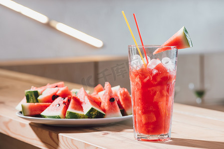 玻璃和木质新鲜西瓜片中加冰西瓜饮料的特写视图
