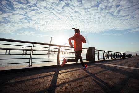 Fitness woman runner running on seaside bridge