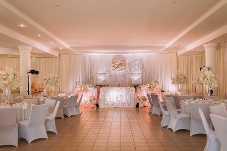 喜庆的婚宴桌上装饰有水晶吊灯、金色烛台、蜡烛和白色粉红花朵。时尚的婚礼日.
