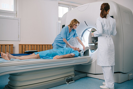 放射科医生在白色外套站在附近的ct扫描仪，而护士准备病人诊断