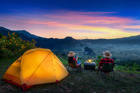 浪漫的情侣在户外露营，日出时用相机拍照。Phu Lang Ka, Pha yao province in Thailand.