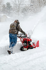 Hard worker uses a snow blower to clean deep snow after a winter storm