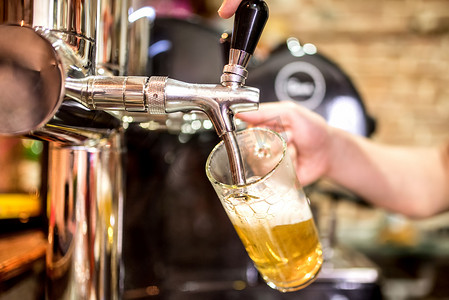 在啤酒的酒保手点击浇注在餐厅或酒吧服役的啤酒生啤酒