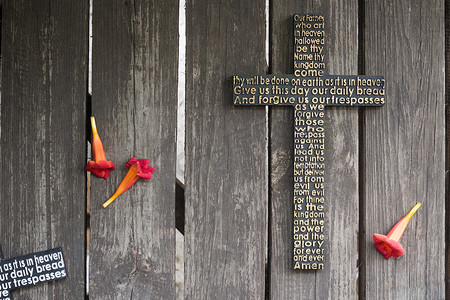开红色花破旧的木板与主祷文黑木制十字架.
