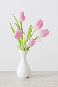 木制桌子上白色陶瓷花瓶中的粉红郁金香 