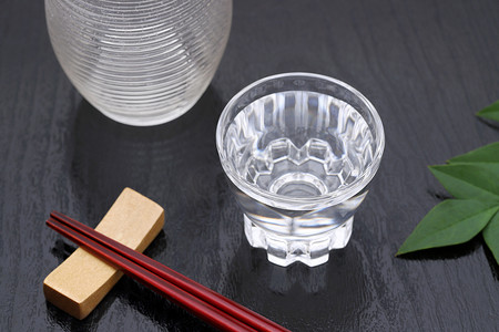 透明玻璃杯中的日本清酒和黑色背景上的罐子