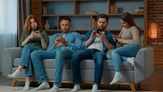 人们坐在沙发上，手机在社交媒体上聊天，忽略了彼此的多种族沉迷。男人和女人都在使用各种不同的工具，现代科技成瘾性的小玩意被滥用