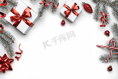 创意圣诞节摄影照片_创意框架由圣诞冷杉树枝，礼品盒，红色装饰，闪光和白色背景的意粉制成。圣诞节和新年假期，bokeh，光。平躺在地上，俯瞰四周