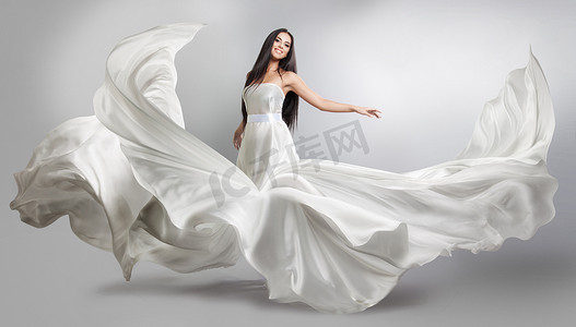 美丽的年轻女孩在飞行白色连衣裙。流动的织物。光白布飞在风中
