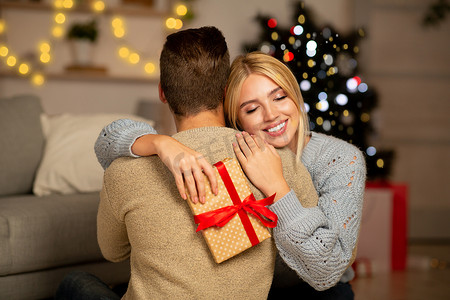 感恩的女人带着圣诞礼物拥抱她的男人
