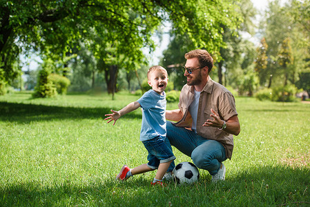 快乐的父亲和儿子在公园的橄榄球球