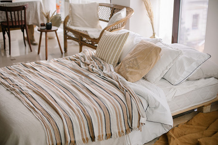 卧室毛毯摄影照片_舒适的卧室。床与枕头和条纹毛毯在舒适的轻便卧室