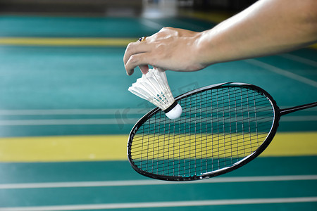 羽毛球手将球拍和白色奶油羽毛球放在网前，然后发到球场的另一边.