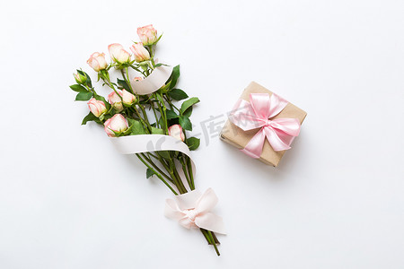 平铺背景图摄影照片_设计理念与粉红色玫瑰花和礼品盒的彩色桌子背景图。节日快乐,母亲节快乐,生日快乐.浪漫的平铺构图.