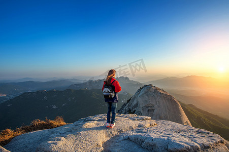 站在山峰上摄影照片_女人站在石头在北汉山国立公园，Seo 的山峰上