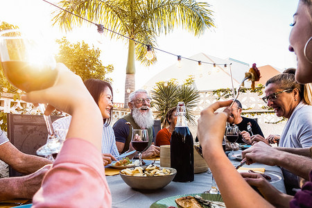 快乐的家庭在日落时间户外做晚餐-一群不同的朋友一起在外面享受有趣的用餐-生活方式的人, 食物和周末活动的概念