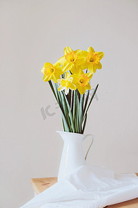 美丽的一束淡黄色的水仙花，盛开在花瓶里，衬托着白色的背景，闭合在一起。文字空间。春天的花朵。母亲节卡片。沉默寡言的生活.