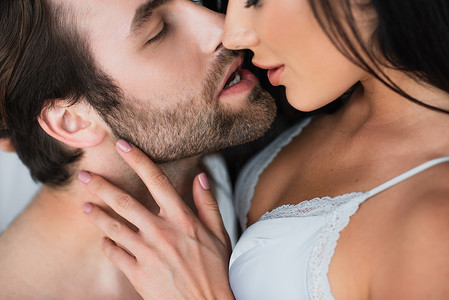 close up of bearded man kissing seductive woman in bra