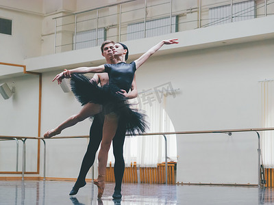 年轻的男子在古典芭蕾与年轻漂亮的女子在健身房的黑色芭蕾舞短裙的服装练习。简约的内饰, 舞蹈性感的舞蹈.